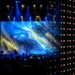 Concert-stage rental LED wall fading into a close-up RGB pixel grid, illustrating pitch at touring scale