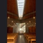 Empty modern church sanctuary with wooden pews looking toward the stage — measure the room before you pick pixel pitch