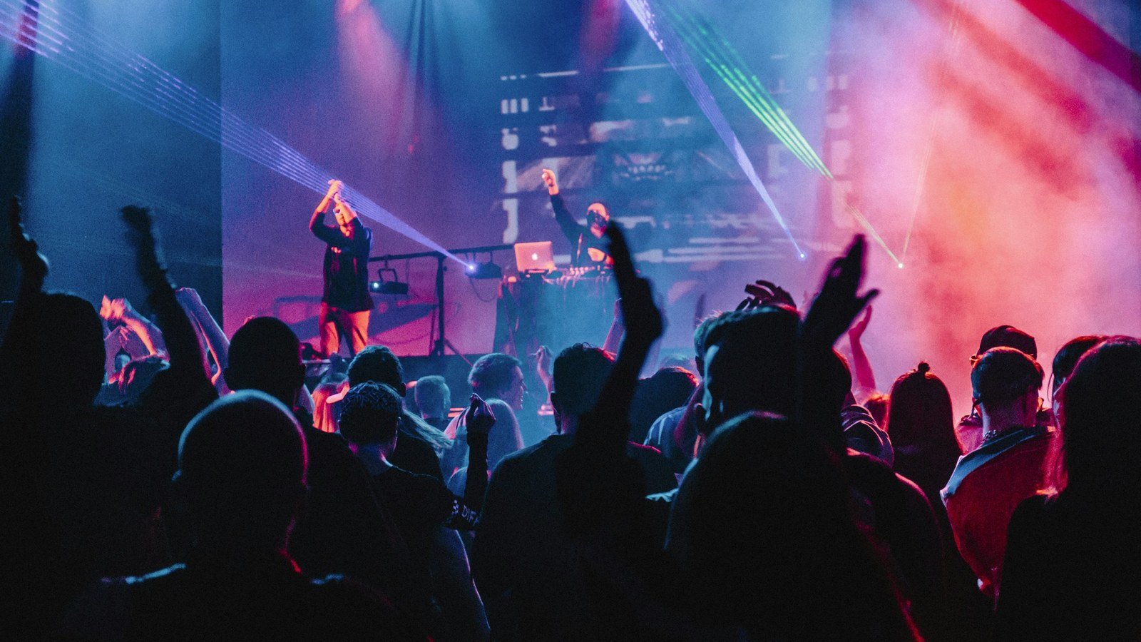Crowd facing a stage with a large LED backdrop — lyrics, IMAG, and cameras change the brief