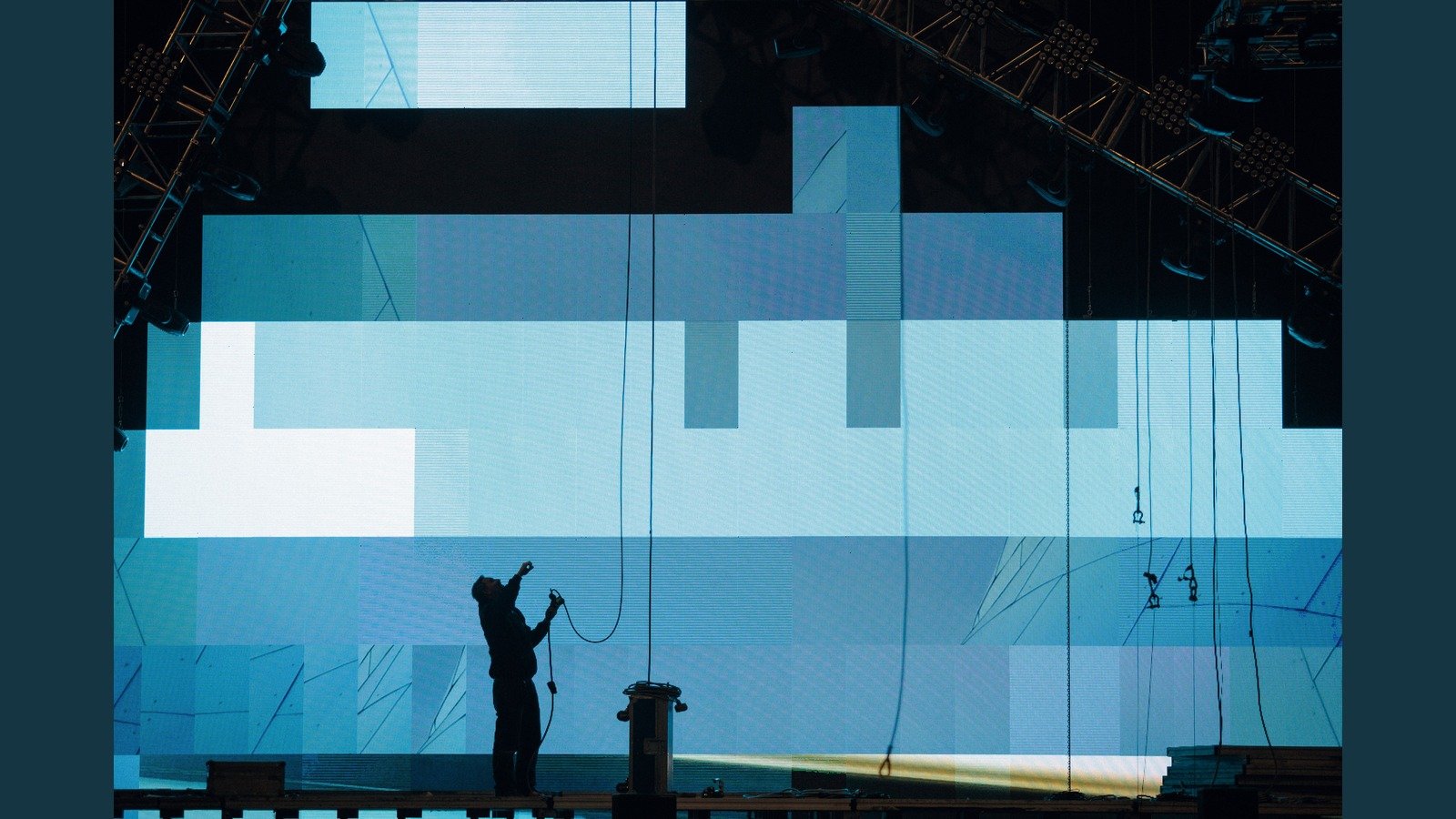 Technician cabling in front of a modular LED wall during setup -- locks, footprint, and crew speed matter at festival load-in