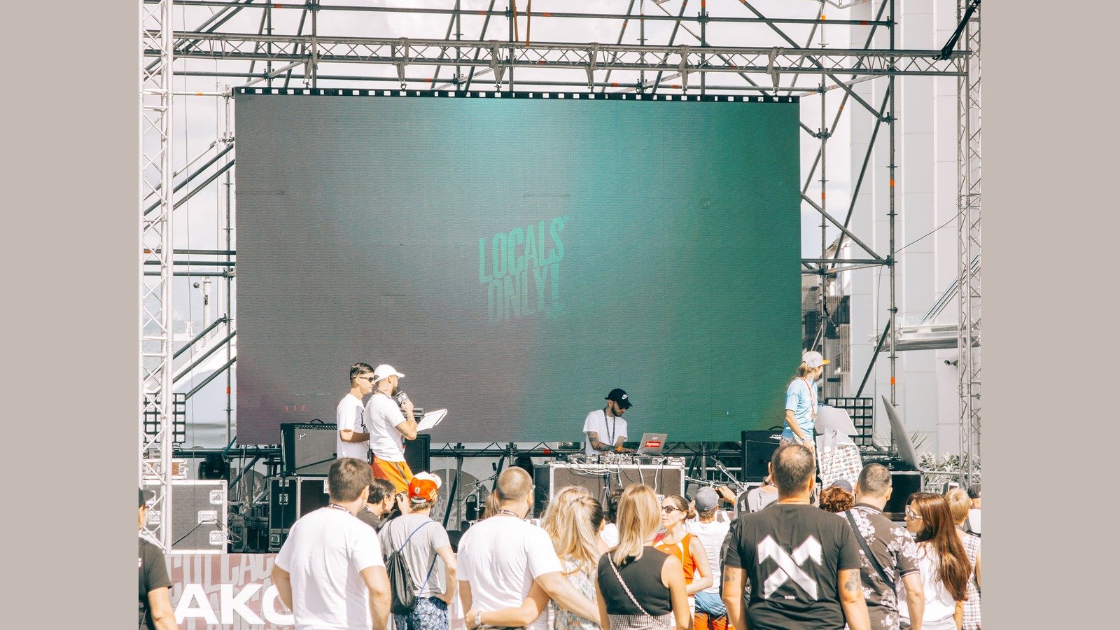 Daytime outdoor LED wall on scaffold with flight cases on the stage deck -- daylight brightness and load-in logistics